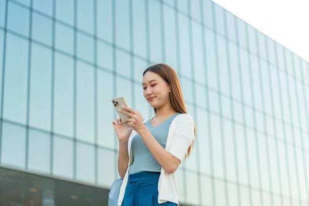 istock Gen Z Asian Woman Using Phone Against A Modern Office Building 1934394477
