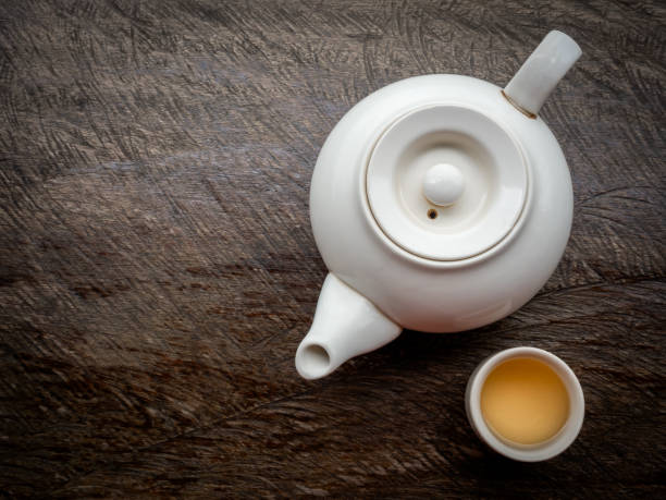istock Teapots set. White traditional ceramic teapot with hot tea water cups preparing on old vintage wooden table background with copy space. 1934398818