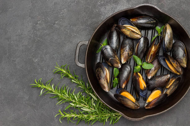 istock Shellfish Mussels in frying pan.  Rosemary and lemon on table. Shellfish seafood 1934403130