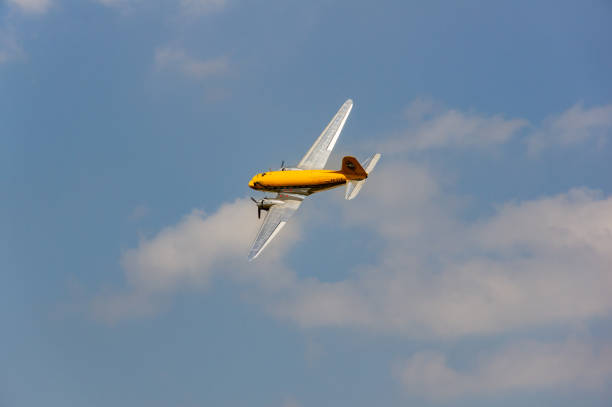 A scale model of a bare-metal DC-3 Dakota in flight, seen here flying over a desert location at dusk.