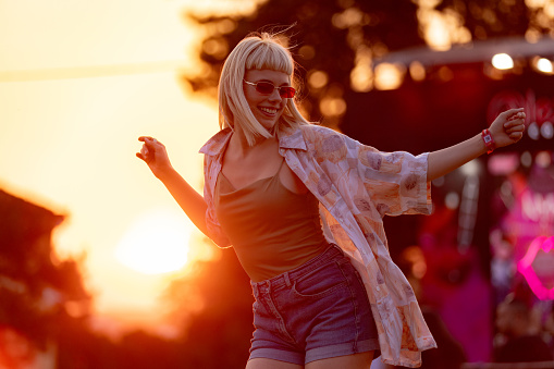 Happy hipster woman dancing on a music festival at sunset.