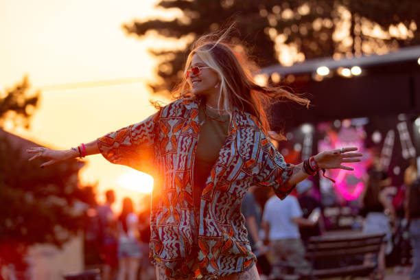glückliche frau, die spaß beim tanzen auf einem open-air-musikfestival bei sonnenuntergang hat. - musikfestival stock-fotos und bilder