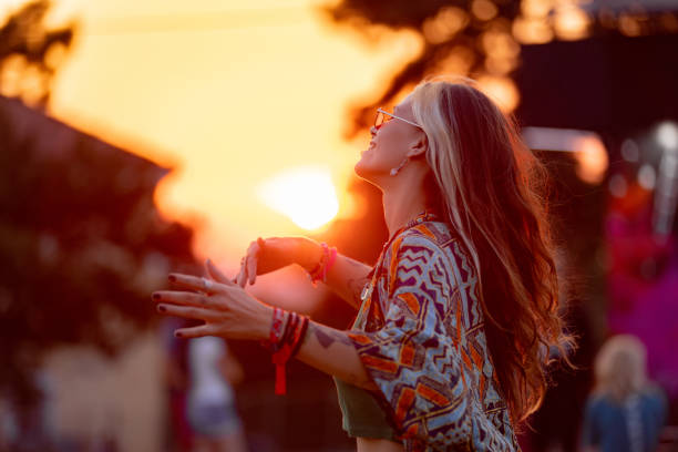 Carefree hipster woman having fun while dancing on an outdoor music festival at sunset.