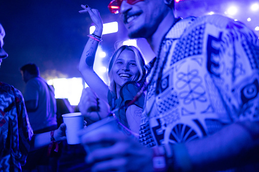 Happy hipster woman having fun while dancing with her friends during the night on a music concert.