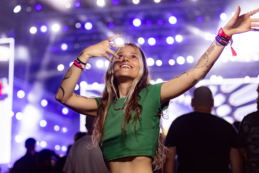 Carefree hipster woman having fun while dancing on a night music concert.