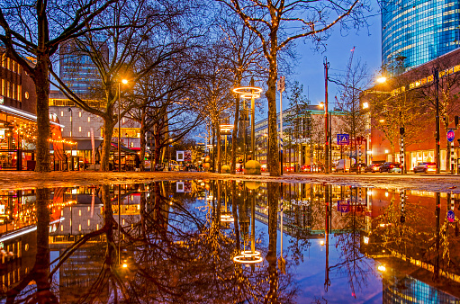 Rotterdam, The Netherlands, November 29, 2023: large puddle after abundant rainfall reflecting the city lights on central Coolsingel boulevard