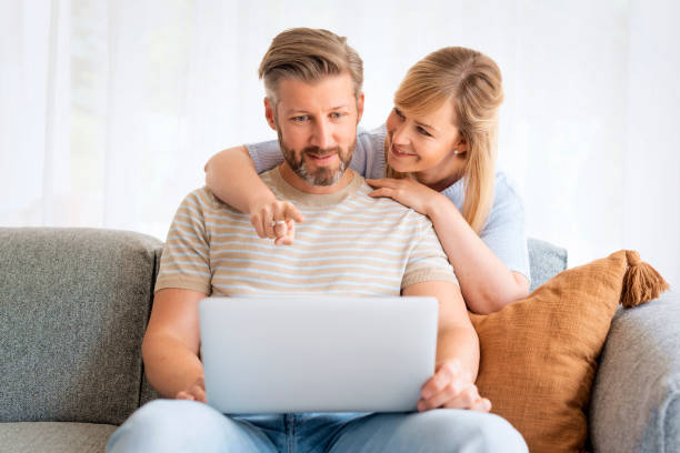istock Woman and man sitting at home on the sofa and using laptop 1934440426