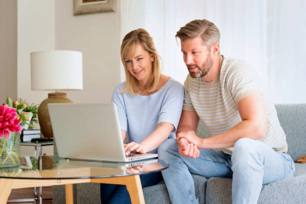 istock Woman and man sitting at home on the sofa and using laptop 1934440430