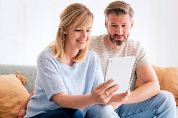 istock Woman and man sitting at home on the sofa and using touchpad 1934440433