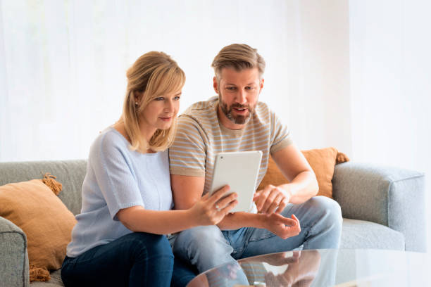 istock Woman and man sitting at home on the sofa and using touchpad 1934440440