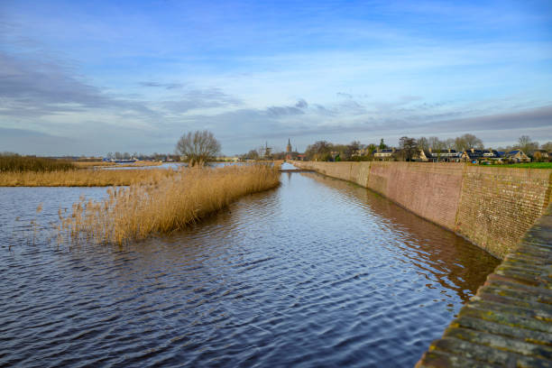 Historical stone dyke along the Zwarte Water near Hasselt with high water level in the river in Overijssel, The Netherlands. The river is overflowing on the floodplains after heavy rainfal upstream in The Netherlands and Germany in December 2023.