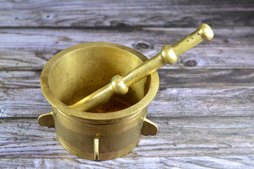 Antique brass copper mortar and pestle, used to prepare ingredients or substances by crushing and grinding them into a fine paste or powder in the kitchen, laboratory, and pharmacy, vintage retro, selective focus