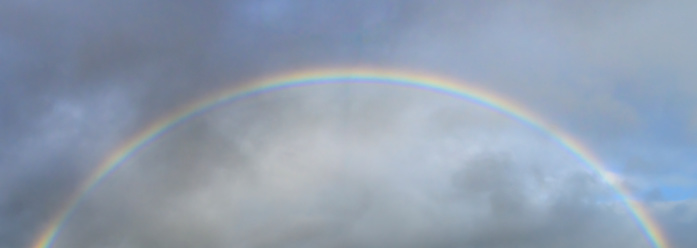 Rainbow with multiple colors in a dark stromy sky during a rainshower.