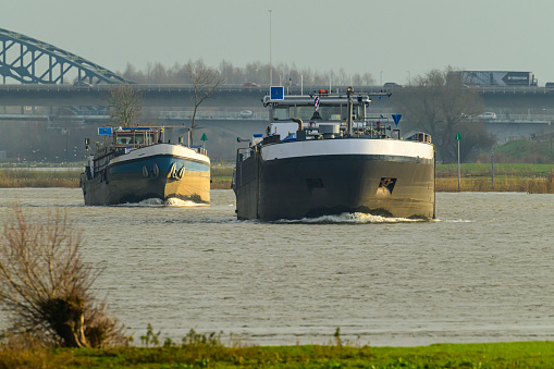 Freight ships sailing downstream on the river IJssel near Zwolle during a winter day.