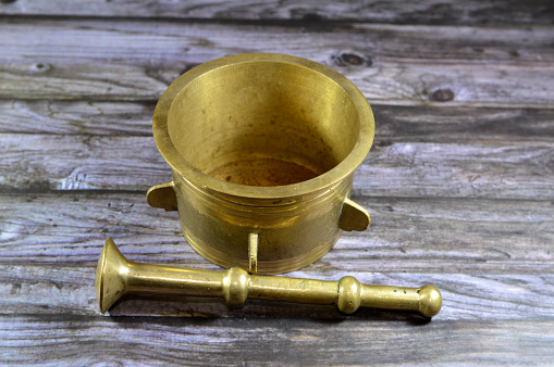 Antique brass copper mortar and pestle, used to prepare ingredients or substances by crushing and grinding them into a fine paste or powder in the kitchen, laboratory, and pharmacy, vintage retro, selective focus