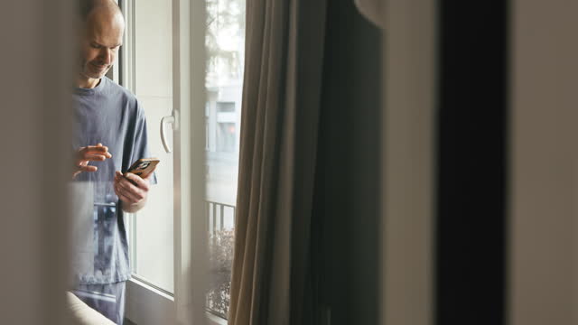 Man in mid 40s text messaging at home