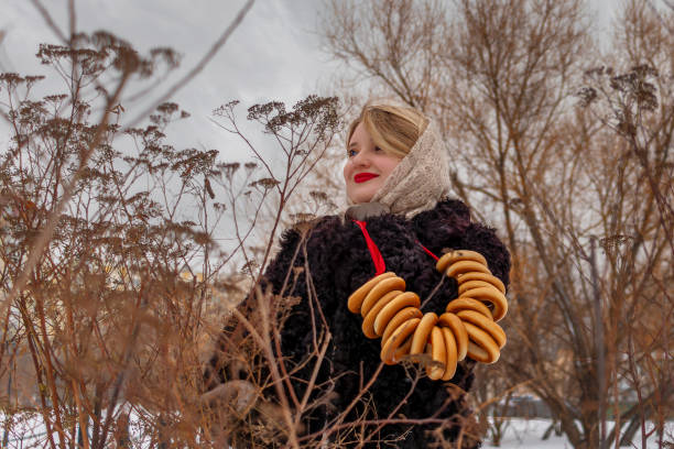 femme russe en manteau de fourrure et châle folklorique en duvet avec des bagels. gras, carême. noyau slave, culture russe - russian culture scarf textile shawl photos et images de collection