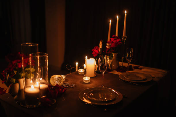 istock Candlelight date in restaurant. Champagne glasses, bouquet flowers. Romantic dinner setup at night. Table setting for couple, Valentine's Day evening, burning candles for surprise marriage proposal. 1934494676