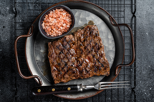 Alternative choice steak - Grilled Skirt or Machete beef meat.  Black background. Top view.