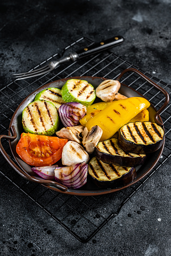 Grilled vegetables, bell pepper, zucchini, eggplant, onion and tomato. Black background. Top view.