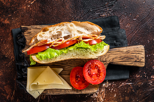 Smoked turkey sandwich with ham, cheese, tomato and Lettuce. Dark background. Top view.