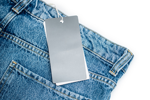 Denim jeans and blank clothing tag isolated on white background.