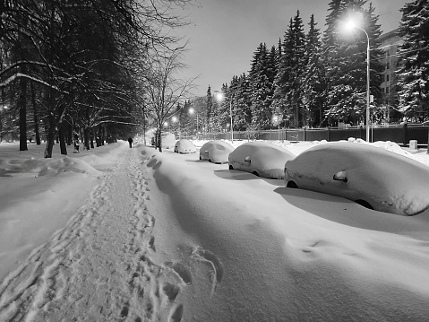 Night street covered with snow in the city. Night winter city. Cars in the Parking lot in the snow.