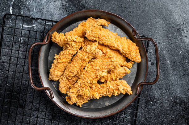istock Crispy chicken tenders strips with Ketchup. Black background. Top view 1934532369
