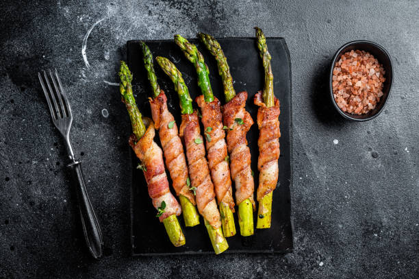 istock Asparagus Baked with bacon and spices. Black background. Top view 1934532502