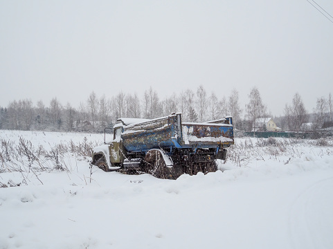 An old abandoned truck in the snow in a ditch on a winter day.