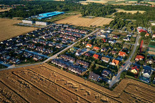 Residential houses in small town near agricultural field, bird eye view. Aerial view of European suburban neighborhood with townhouses. Real estate in Poland