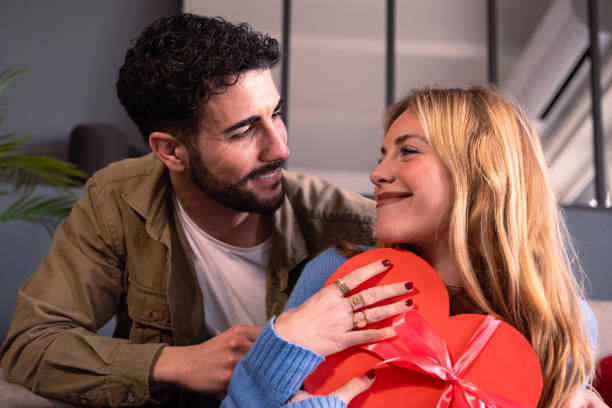 istock Young couple looking lovingly at each other with heart-shaped gift box. Valentine's Day Celebration. 1934538632