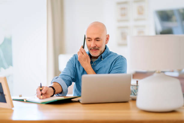 istock Middle aged businessman using smartphone and laptop while working from home 1934545446