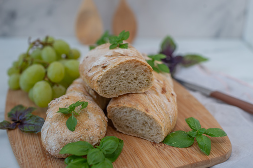 sliced french baguette with crumbs and fresh herbs on a table
