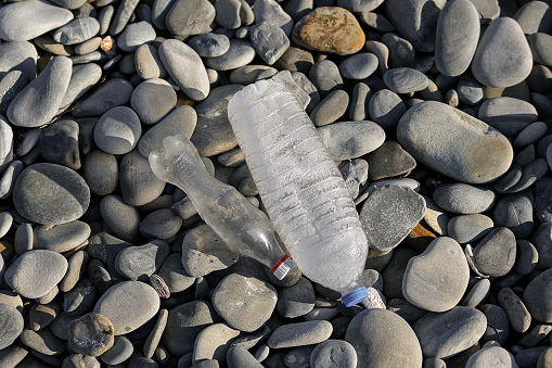 Plastic bottles on a pebble beach, close-up photo, ecology concept.