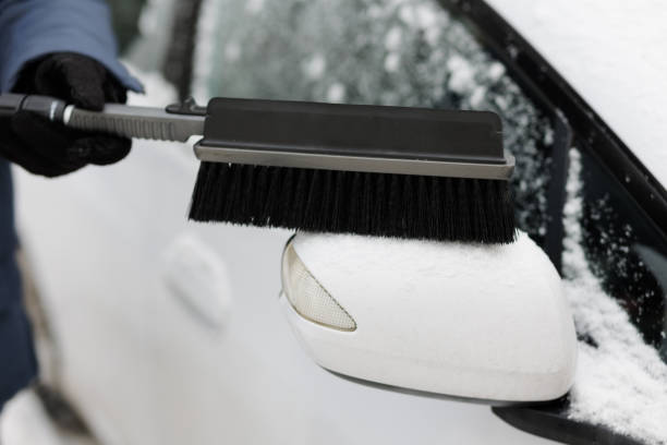 istock hand holding brush and cleaning car after a snowfall 1934585054