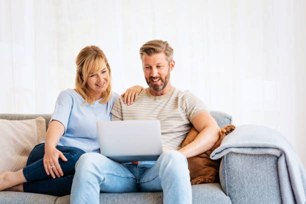 istock Happy couple using laptop while relaxing on the couch at home 1934610001