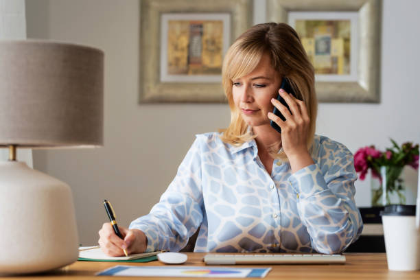 istock Blond haired businesswoman using her mobile phone while working from home 1934610403