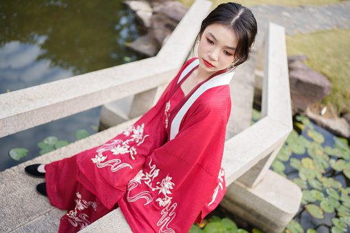 Woman wearing red Hanfu sitting in the park