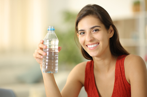 Happy woman showing water bottle at camera