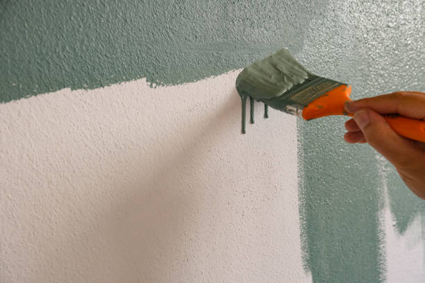 Repairman painting white wall in apartment green using brush, closeup Repairman painting white wall in apartment green using brush, closeup homeward stock pictures, royalty-free photos & images