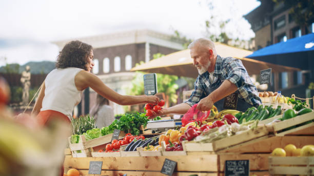 Young Beautiful Customer Shopping for Fresh Natural Vegetables for a Mediterranean Dinner. Black Female Buying Bio Tomatoes and Ecological Local Garlic From a Happy Senior Street Vendor