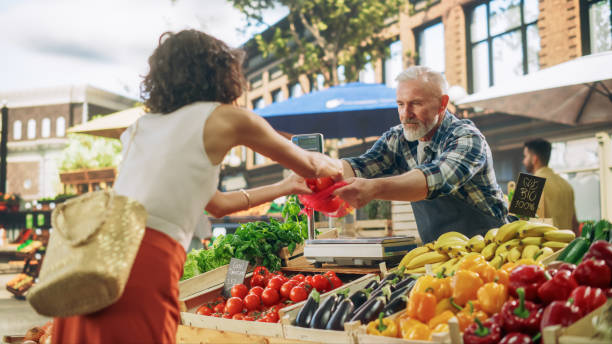 istock Young Beautiful Customer Shopping for Fresh Natural Vegetables for a Mediterranean Dinner. Black Female Buying Bio Tomatoes and Ecological Local Garlic From a Happy Senior Street Vendor 1934639718
