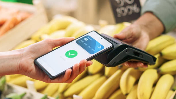 istock Sustainability-Conscious Consumer Buying Organically Sourced Farm Produce Using a Digital E-Money Software to Pay with Smartphone Through Contactless NFC Technology on a Bank POS Terminal 1934644635
