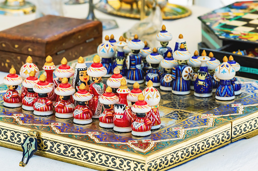 Handmade wooden colorful chess in the form of Uzbek figures. Tourism, souvenir, shoping. Khiva (Xiva), Uzbekistan