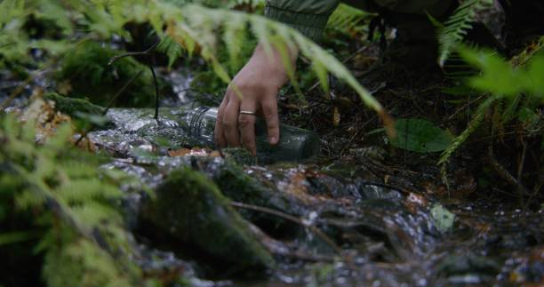 istock Tourist comes to gather water from clear stream into bottle 1934653797