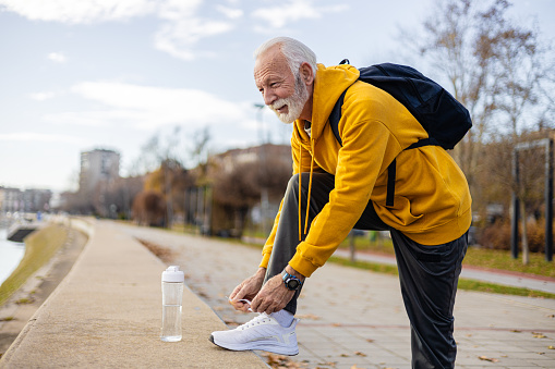 Shot of a mature senior man holding his knee while exercising outdoors in active sportswear