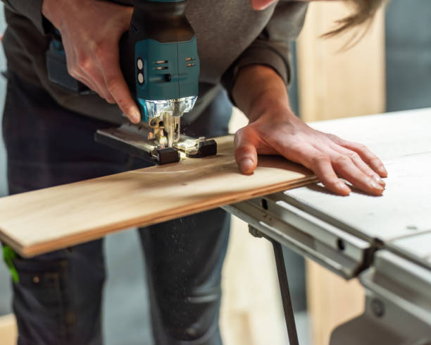 istock Man saws wooden shelf on saw table with jig saw. 1934660765
