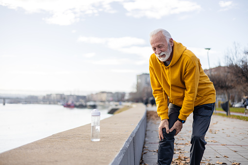 Shot of a mature senior man  holding his knee while exercising outdoors in active sportswear