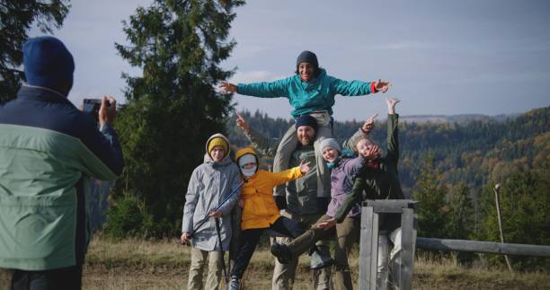 istock Diverse tourists smile and wave at camera standing against mountains landscape 1934677394
